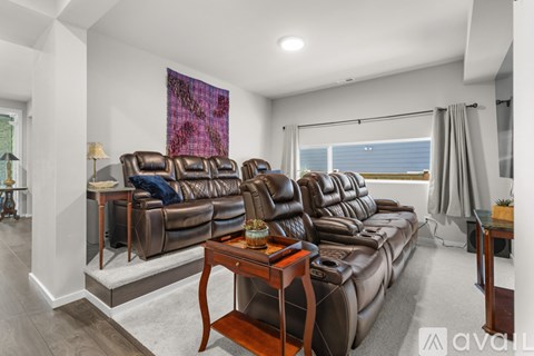 A living room with a brown leather sofa and a purple abstract painting on the wall.
