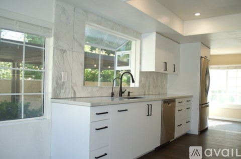 A kitchen with white cabinets and a marble countertop.