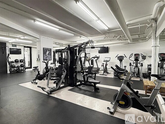 A gym with a variety of equipment including treadmills, weights, and exercise machines.