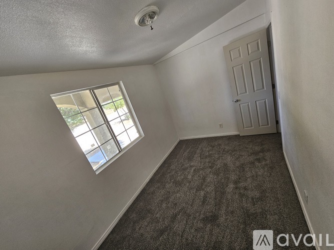 A room with a carpeted floor, a window, and a door.