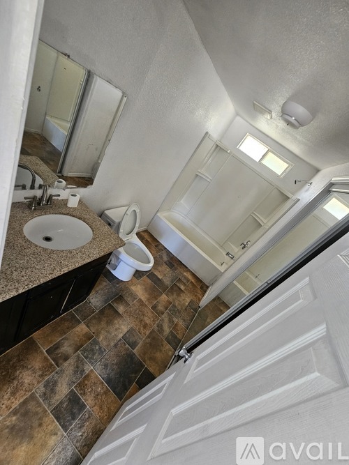 A bathroom with a brown tiled floor and a white door.