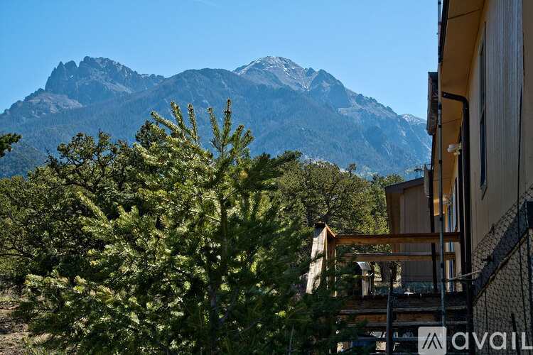 A mountain range is in the background of a building with a tree in the foreground.