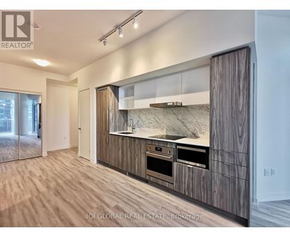A modern kitchen with wooden cabinets and a marble backsplash.