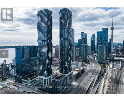 Two tall buildings are in the foreground of a cityscape with a highway and other buildings in the background.