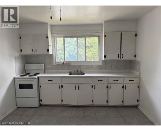 A kitchen with white cabinets and a window.