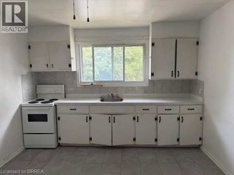 A kitchen with white cabinets and a window.