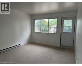 A room with a door, windows and a carpeted floor.