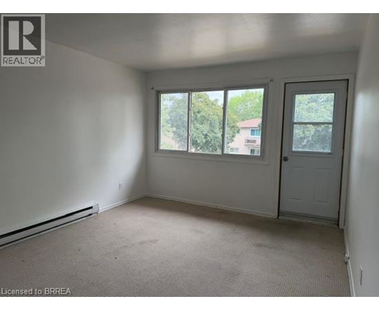 A room with a door, windows and a carpeted floor.