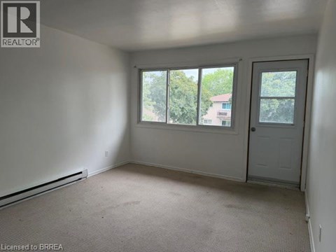 A room with a door, windows and a carpeted floor.