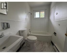 A white bathroom with a tub, toilet and sink.