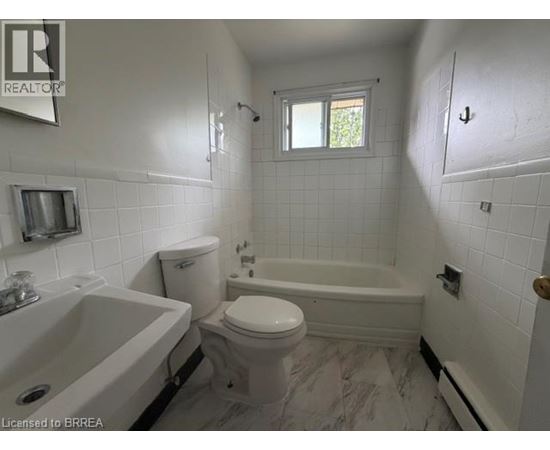 A white bathroom with a tub, toilet and sink.