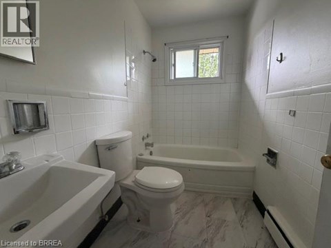 A white bathroom with a tub, toilet and sink.