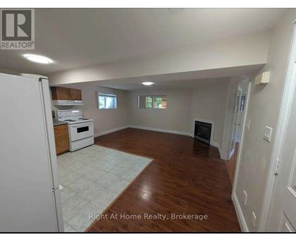 A spacious room with wood flooring and a white refrigerator.