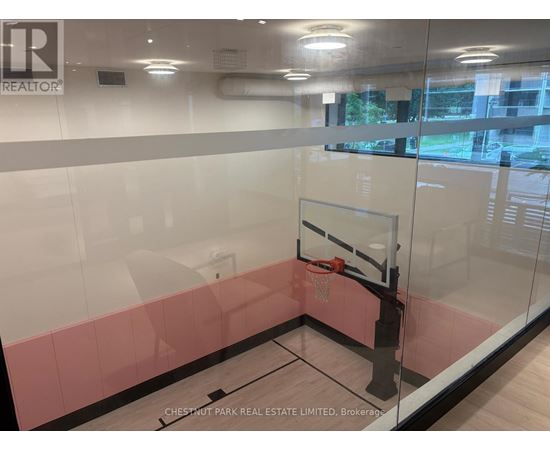 A basketball hoop is mounted on a glass wall in a room.