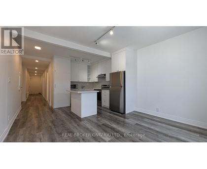 A spacious kitchen with white cabinets and a stainless steel refrigerator.