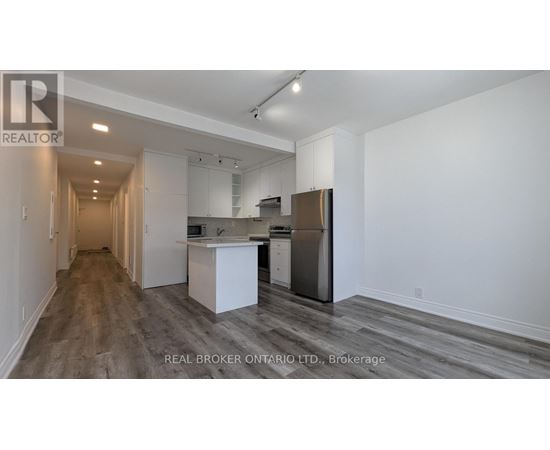 A spacious kitchen with white cabinets and a stainless steel refrigerator.