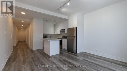 A spacious kitchen with white cabinets and a stainless steel refrigerator.