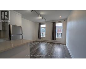 A spacious kitchen with a refrigerator, cabinets, and a countertop.