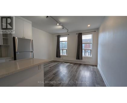 A spacious kitchen with a refrigerator, cabinets, and a countertop.