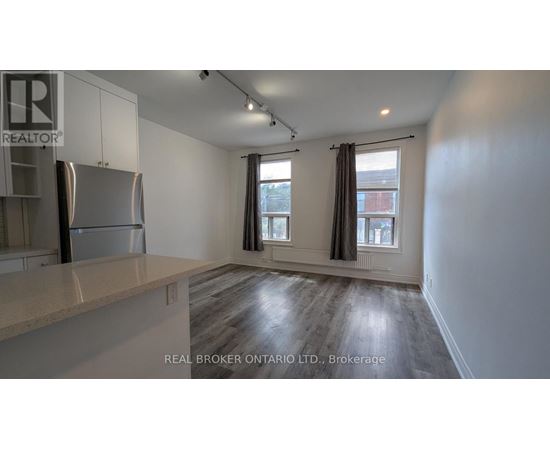 A spacious kitchen with a refrigerator, cabinets, and a countertop.