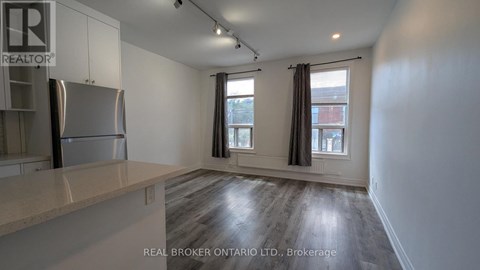 A spacious kitchen with a refrigerator, cabinets, and a countertop.