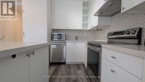 A kitchen with white cabinets and a microwave above the dishwasher.