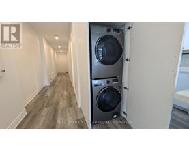 A long hallway with a washer and dryer in a doorway.