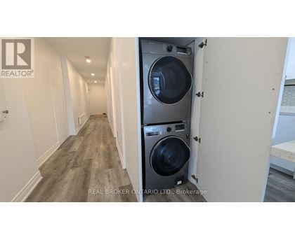 A long hallway with a washer and dryer in a doorway.