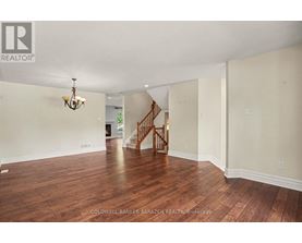 A spacious room with wooden floors and a staircase.
