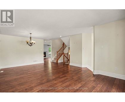 A spacious room with wooden floors and a staircase.