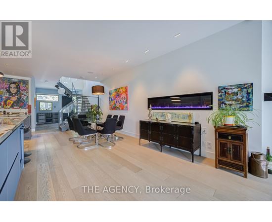 A living room with a wooden floor and a large painting on the wall.