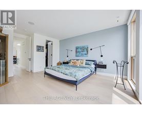 A bedroom with a bed, a nightstand, and a chair.