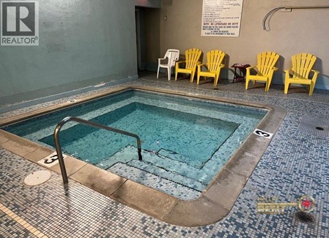 A pool with a metal ladder and yellow chairs.