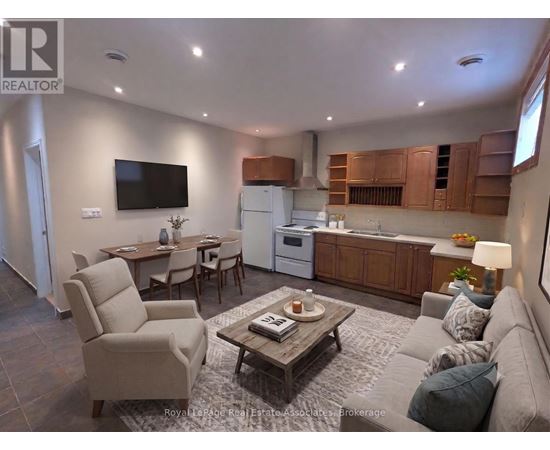 A living room with a couch, chairs, a coffee table, and a television.