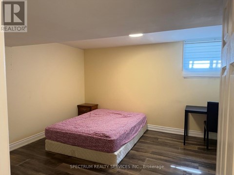A bedroom with a pink bedspread and a small bed.