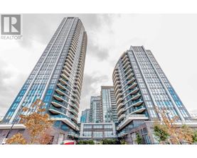 Two tall buildings with balconies are in the foreground with a cloudy sky in the background.