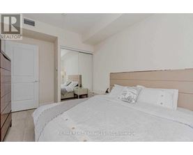 A bedroom with a large bed and a small bedside table.