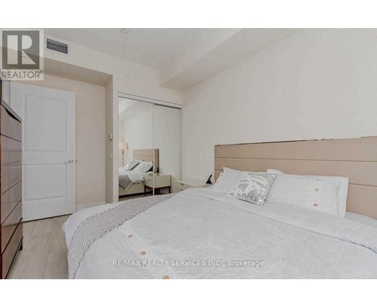 A bedroom with a large bed and a small bedside table.