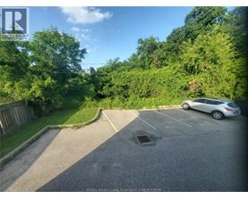 A car is parked in a parking lot with trees in the background.