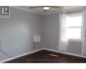 A room with a ceiling fan and a window with white curtains.