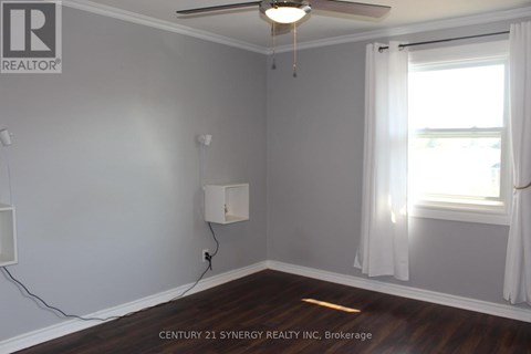 A room with a ceiling fan and a window with white curtains.