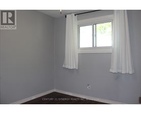 A room with a window and curtains, with a logo on the wall.