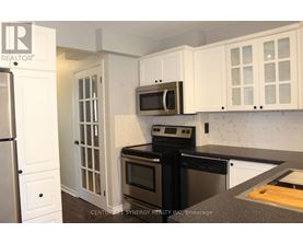 A kitchen with white cabinets and black appliances.