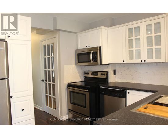A kitchen with white cabinets and black appliances.