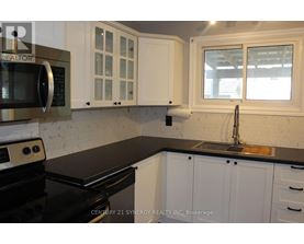 A kitchen with white cabinets and black countertops.