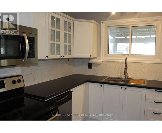 A kitchen with white cabinets and black countertops.