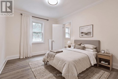 A bedroom with a large bed and a window with curtains.