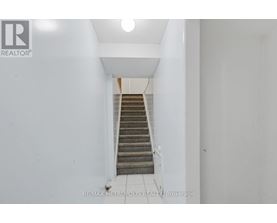 A staircase in a white hallway with a logo on the wall.