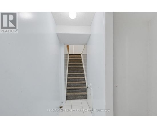 A staircase in a white hallway with a logo on the wall.