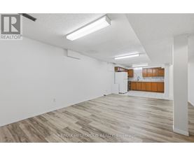 A spacious room with wooden flooring and white walls.